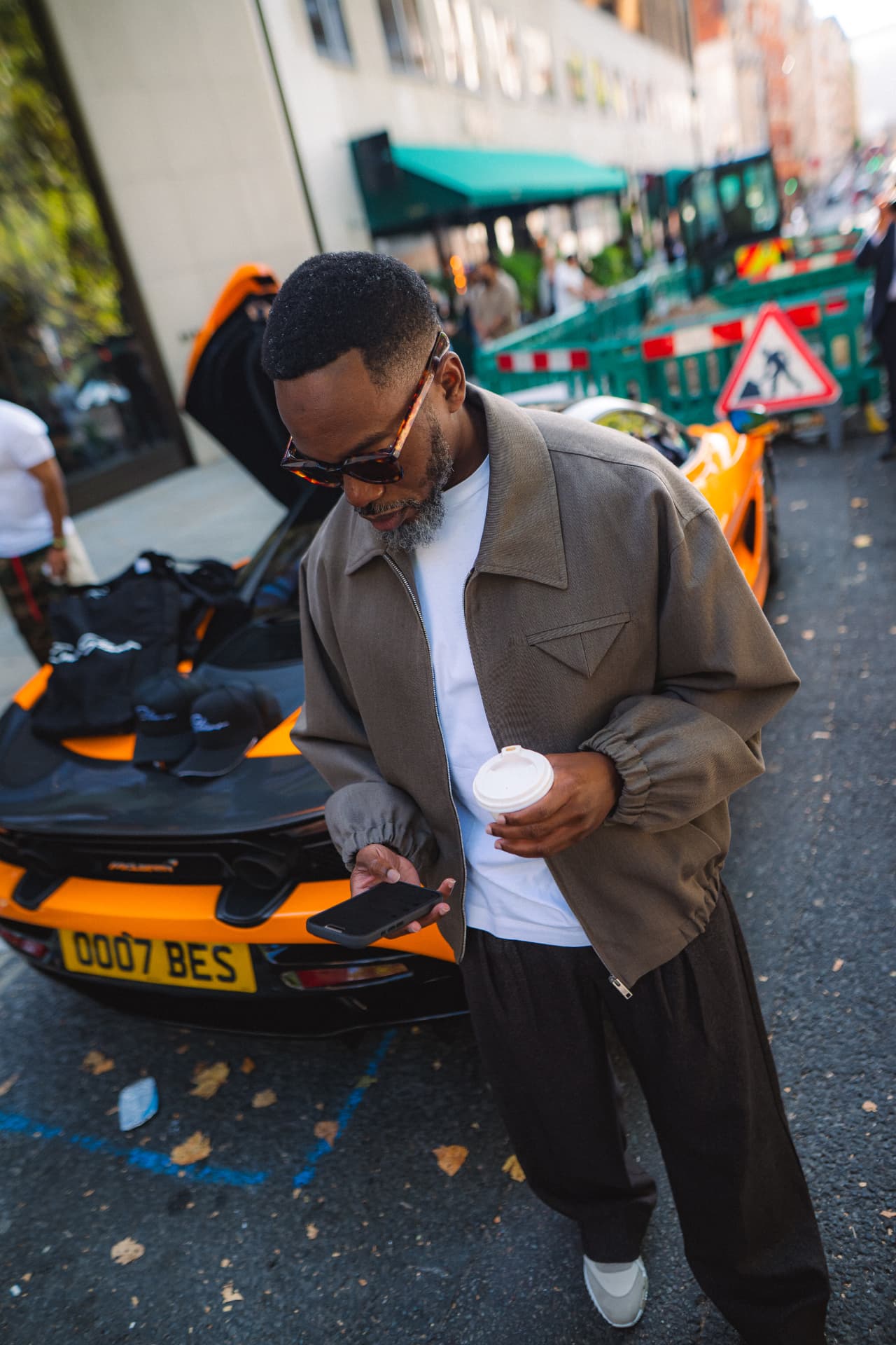 Guest with coffee beside an orange McLaren